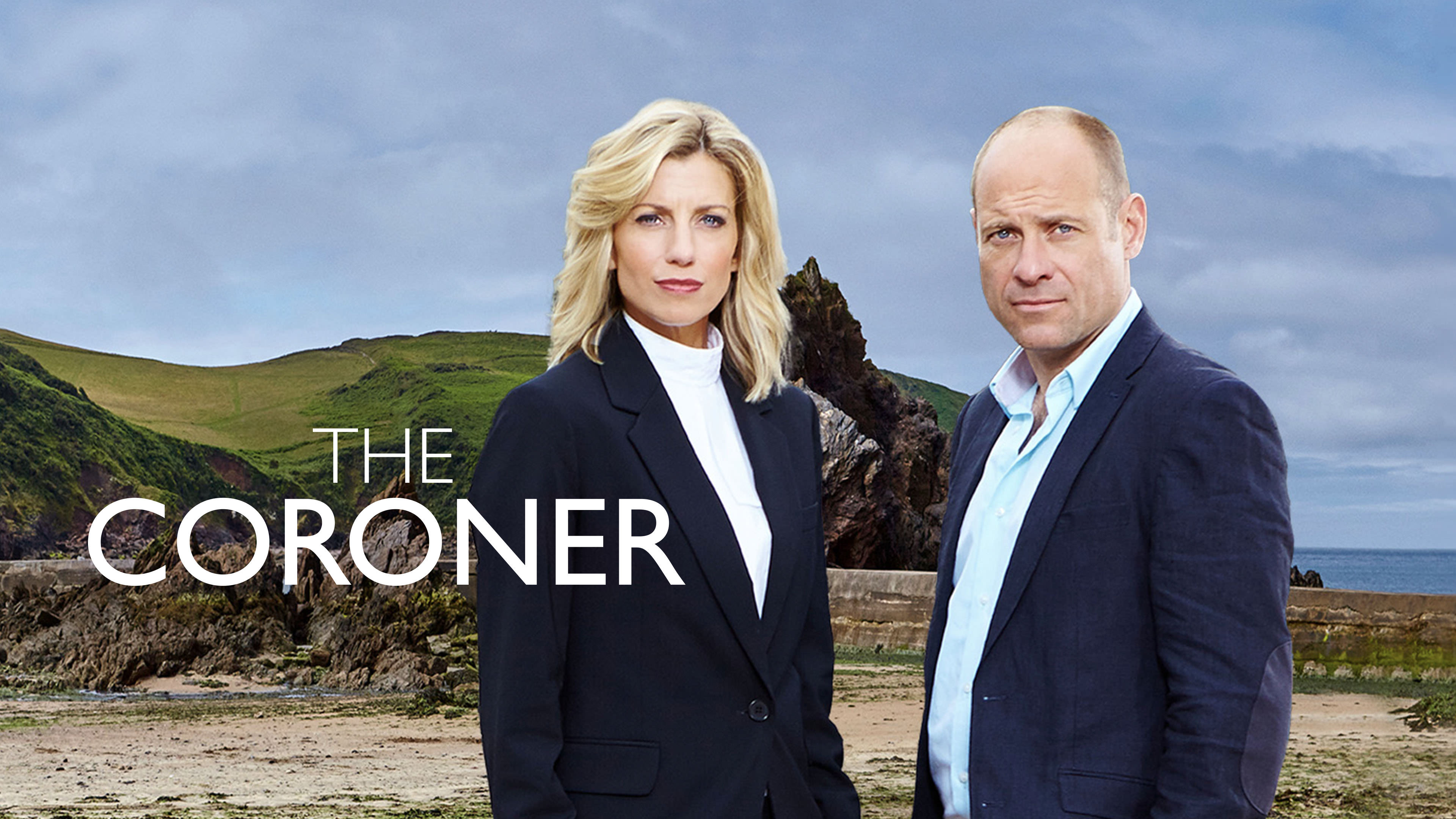 Jane Kennedy and Davey Higgins standing on a beautiful, sun-drenched Devon beach from the series The Coroner.